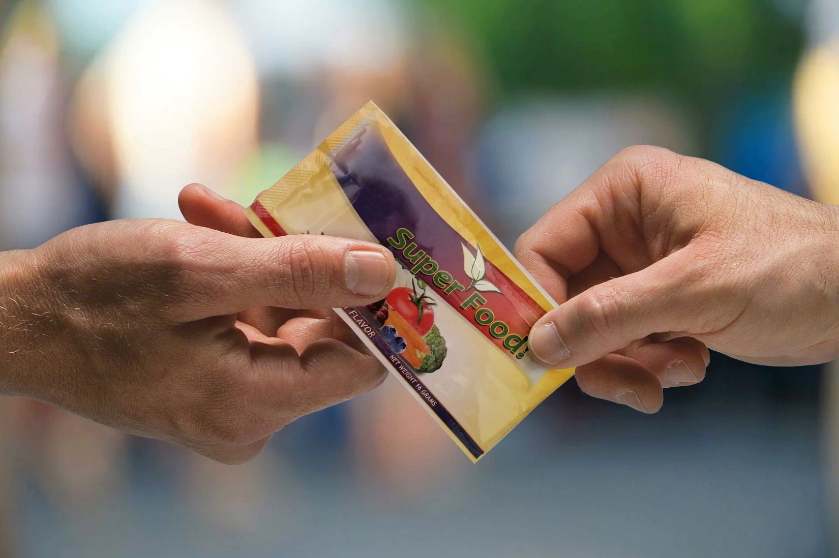Two hands exchanging a Super Food packet with a blurred background.