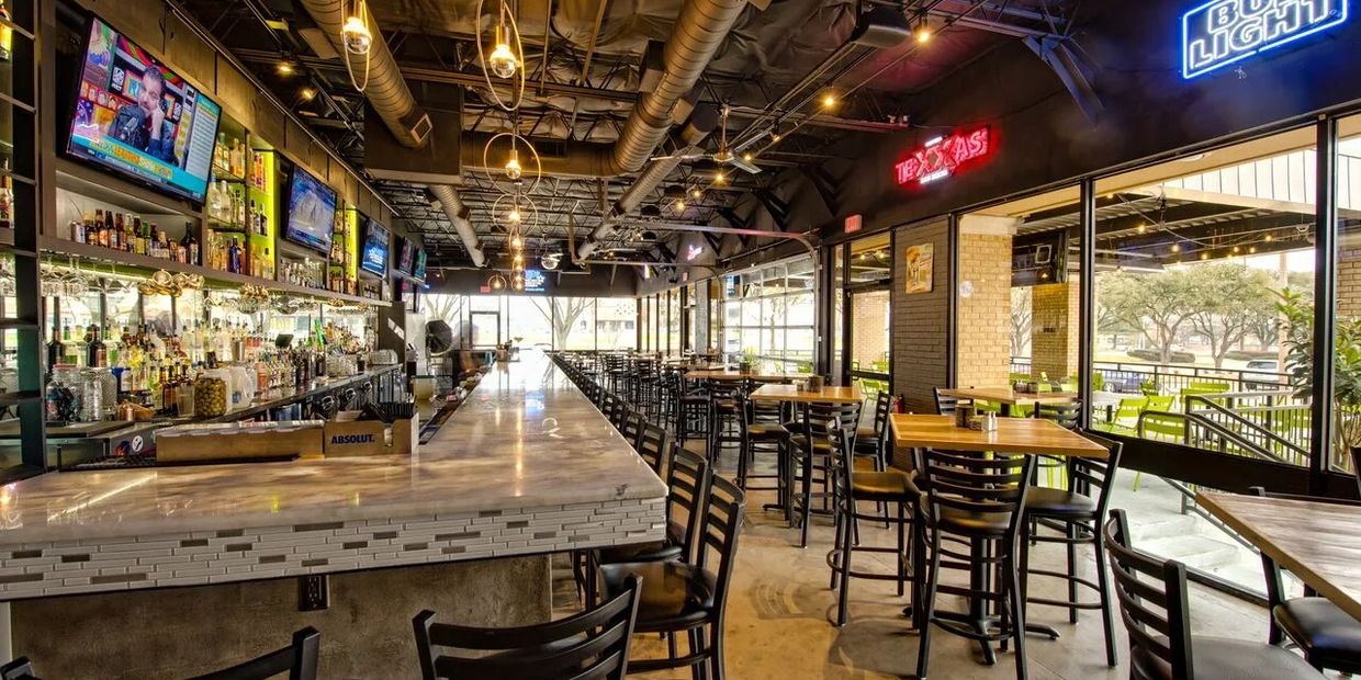 Modern bar and dining area with neon signs and multiple TVs.