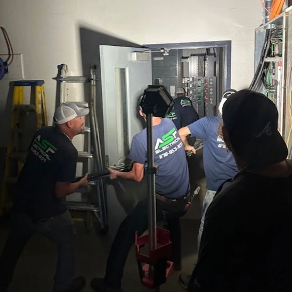 Team installing industrial electrical panel.