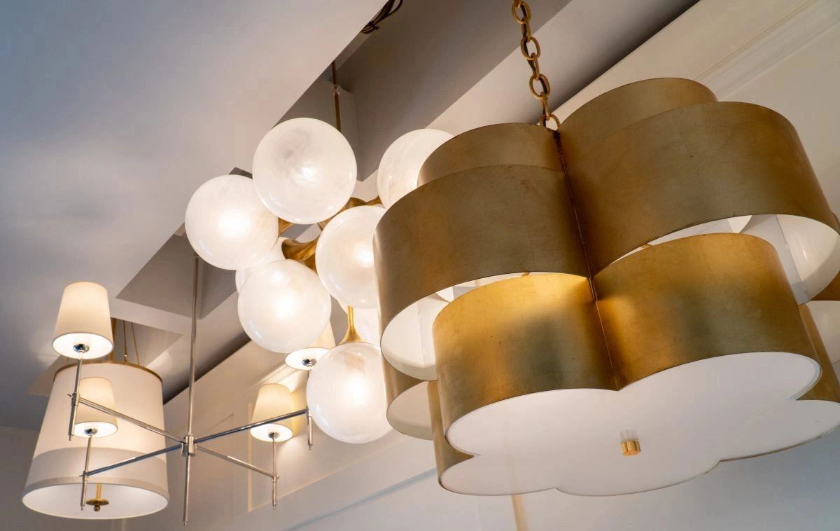 Three distinct modern chandeliers with white and gold designs hanging from the ceiling.
