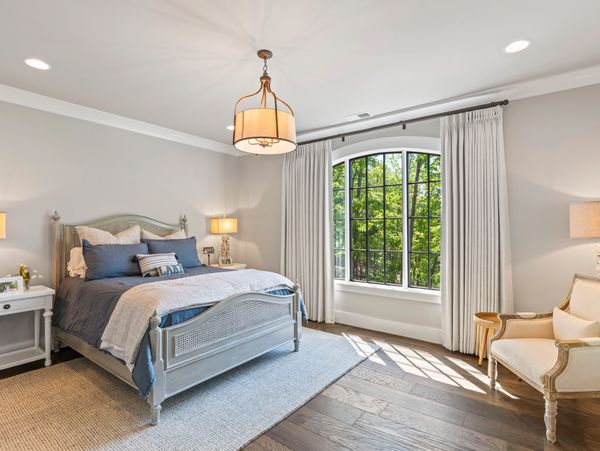 Bright bedroom with large arched window and elegant decor.
