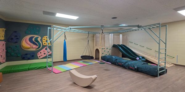 Indoor sensory play area with swings, slides, and climbing wall.