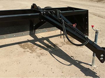 Close-up of a black trailer hitch and support stand on dirt.