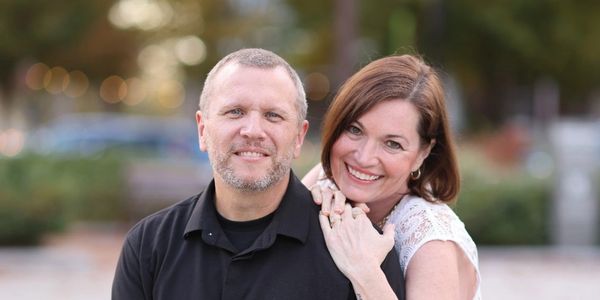 Smiling couple posing outdoors with blurred background.
