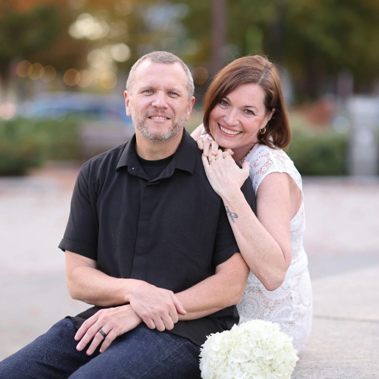 Smiling couple posing outdoors with blurred background.
