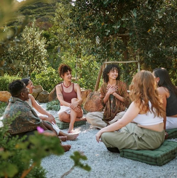 A group of six women sitting in a circle outdoors, enjoying a peaceful conversation.