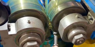 Close-up of industrial rollers with a small metal rod held in the foreground.
