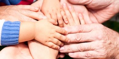 Multiple hands of different ages stacked together, symbolizing unity and support.