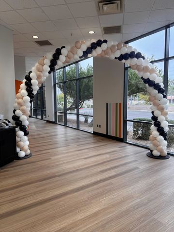 Black, white, and pink balloon arch indoors.