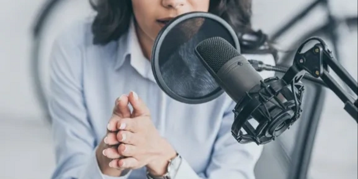 Woman speaking into a professional microphone with a pop filter.