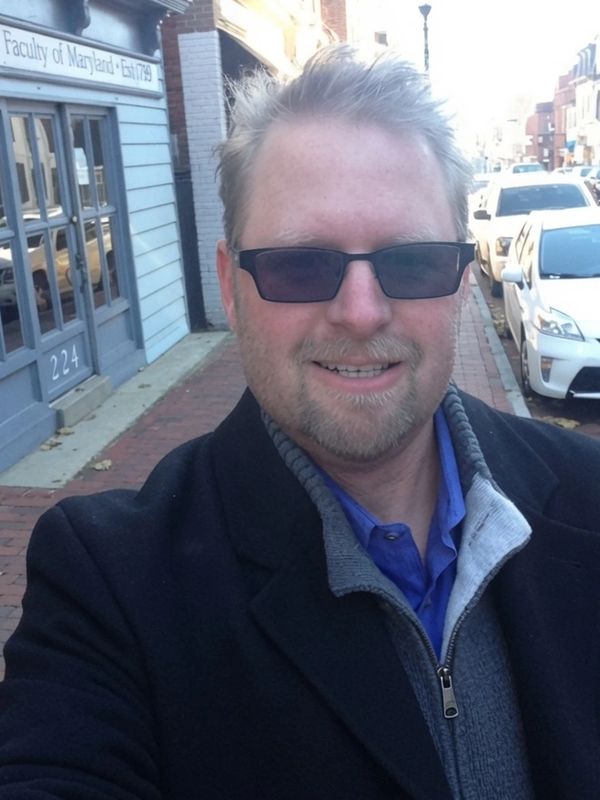 Man taking selfie on a city street with sunglasses.