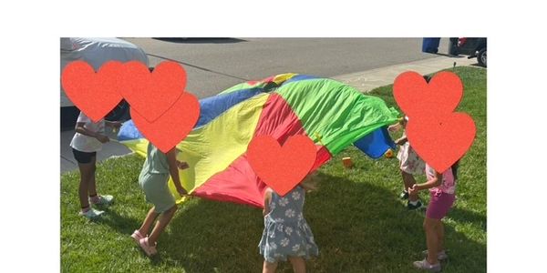 Children playing with a colorful parachute on a sunny day.