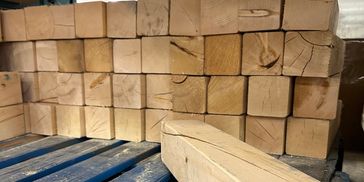 Stacked wooden beams on a pallet in a warehouse.