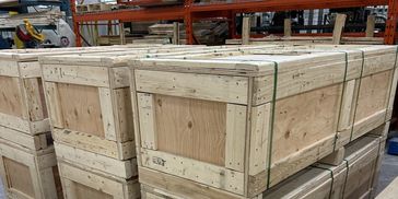 Stacked wooden crates secured with metal straps in a warehouse.