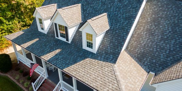 Aerial view of a house with gray shingle roof and dormer windows.