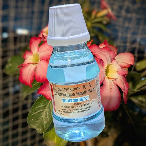 A bottle of Surgihex mouthwash with pink flowers in the background.