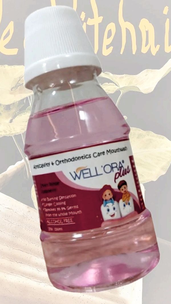 Bottle of Well Ora Plus anticavity and orthodontic mouthwash with pink liquid.