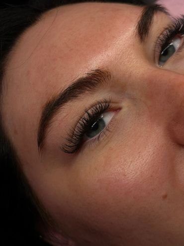 Close-up of an eye with long eyelashes and well-groomed eyebrows.