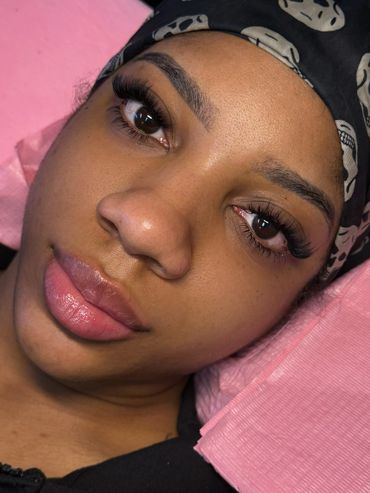 Close-up of a woman with flawless eyelash extensions and a skull-patterned headscarf.
