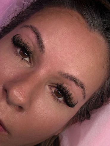 Close-up of a woman's face showcasing long, voluminous eyelash extensions.