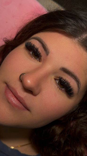 Close-up of a woman with dramatic eyelashes and nose ring.