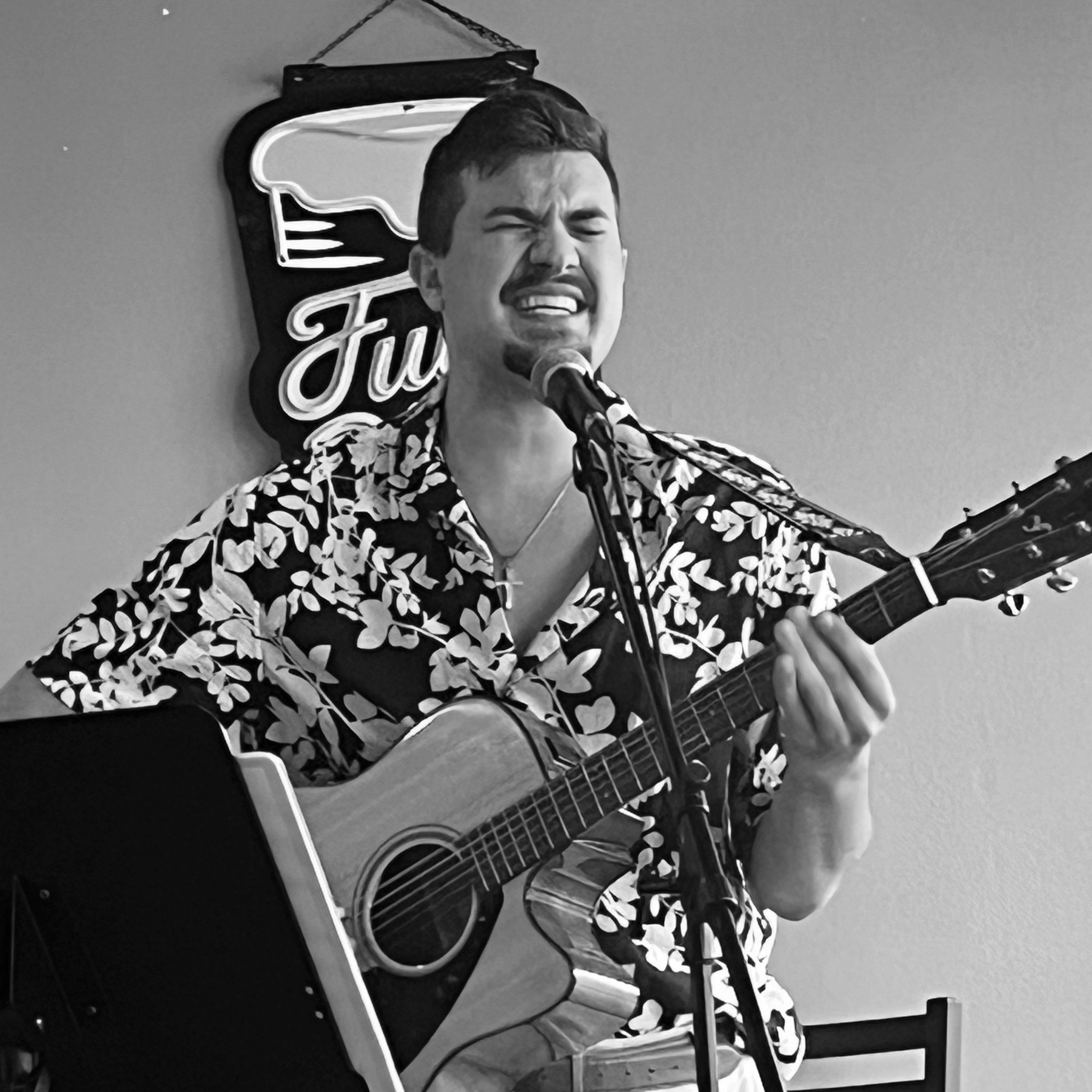 Man passionately singing and playing guitar in a casual setting.