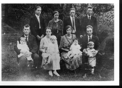 Black and white photo of a family with adults and children outdoors.
