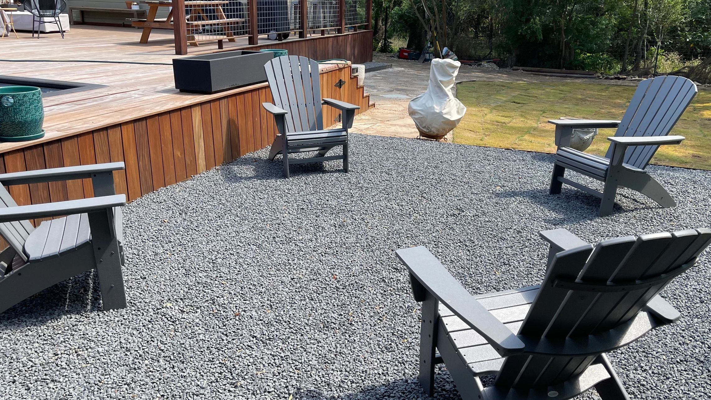A cozy backyard seating area with four chairs arranged in a circle over a patio of blackstar gravel