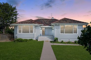 A single-story house with a well-maintained lawn during sunset.
