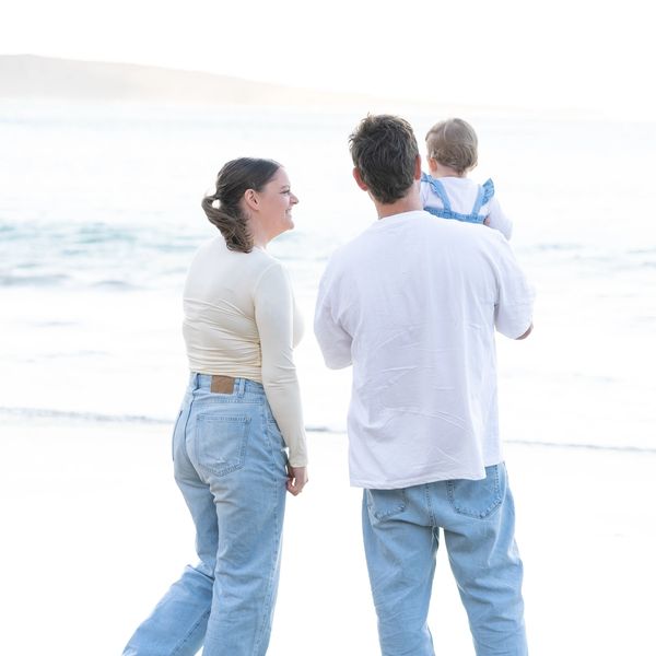 Family enjoying a day at the beach, standing barefoot by the shore.
