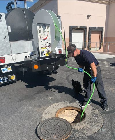 Worker using equipment to clean or inspect a sewer manhole.