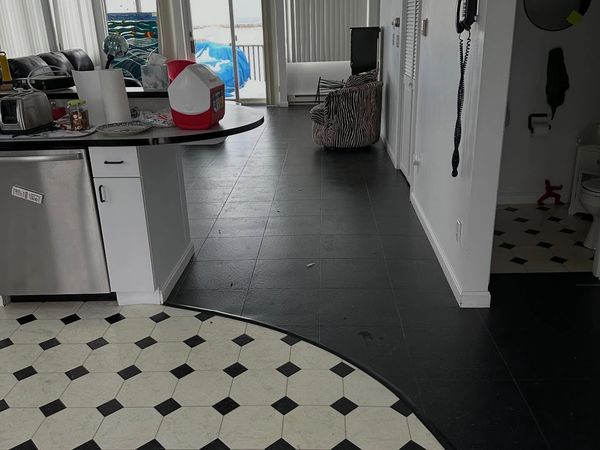 Indoor view of a kitchen and living area with black and white tiled floors.