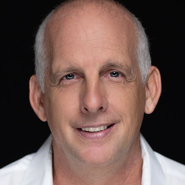 Close-up portrait of a smiling middle-aged man with light skin and blue eyes.