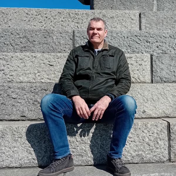 Man sitting on stone steps in sunlight.