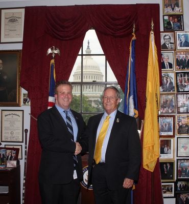 Two men in suits shaking hands with the U.S. Capitol in the background.