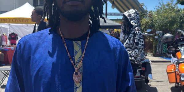 Man wearing blue traditional outfit and gold chains.