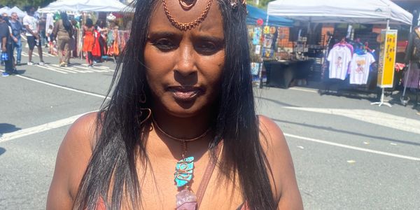 Woman wearing tribal jewelry at an outdoor market.