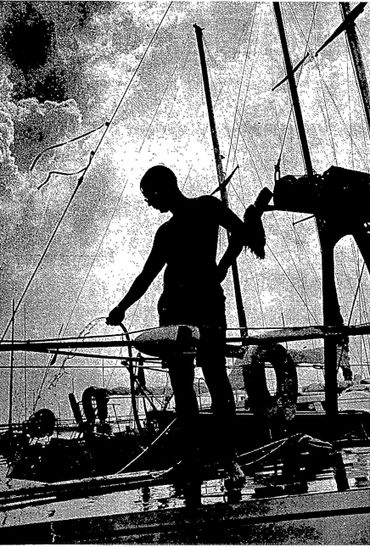 Silhouette of a person on a boat with rigging and a cloudy sky.