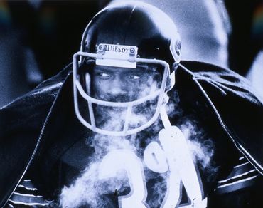 Football player wearing helmet and number 34 jersey amid mist or smoke.
