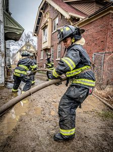 African American female firefighter pulling hose.