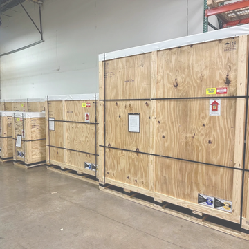 Large wooden crates lined up in a warehouse on pallets.