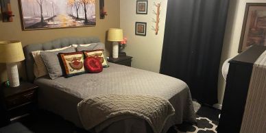 Cozy bedroom with gray bedding and art on the wall.