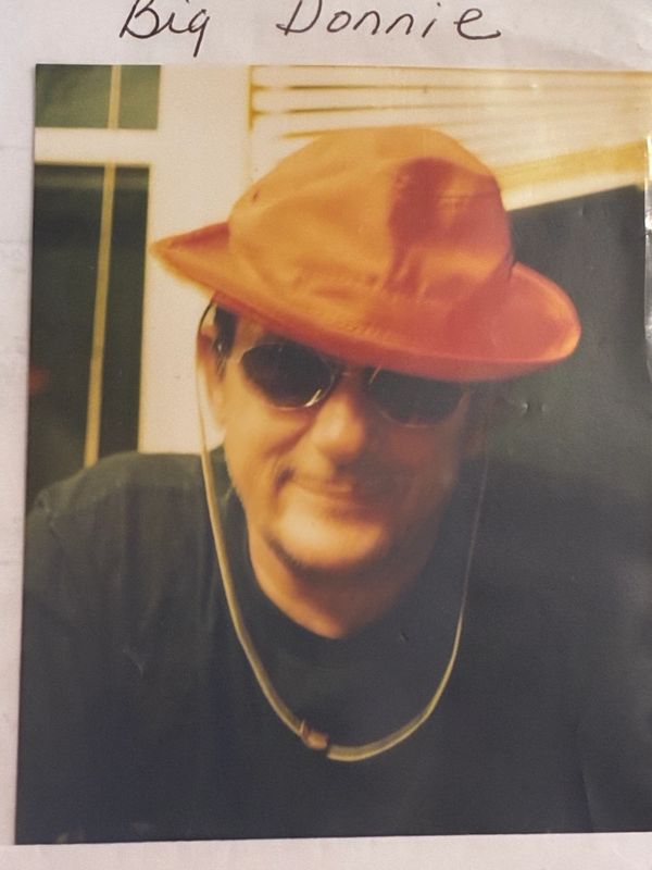 Man with sunglasses and orange hat smiling.