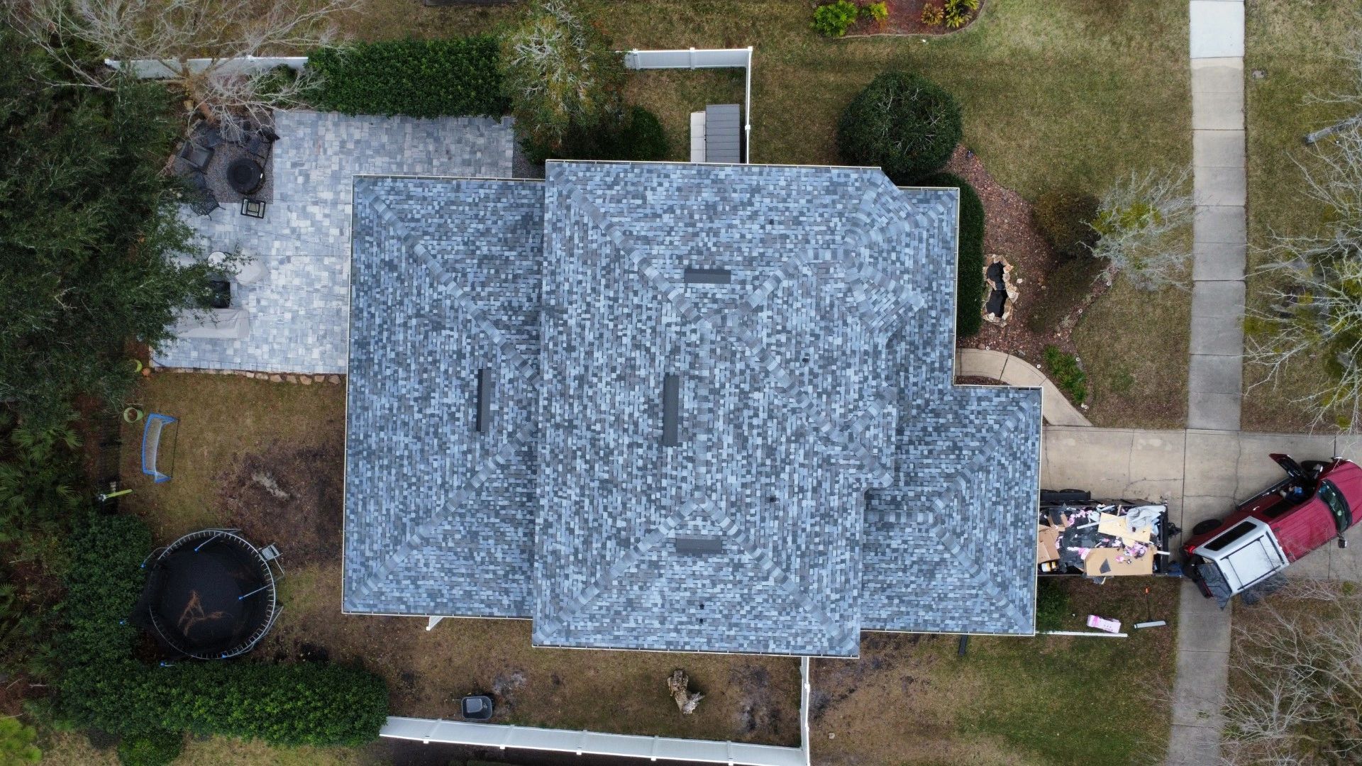 Aerial view of a house with a repaired roof and backyard.