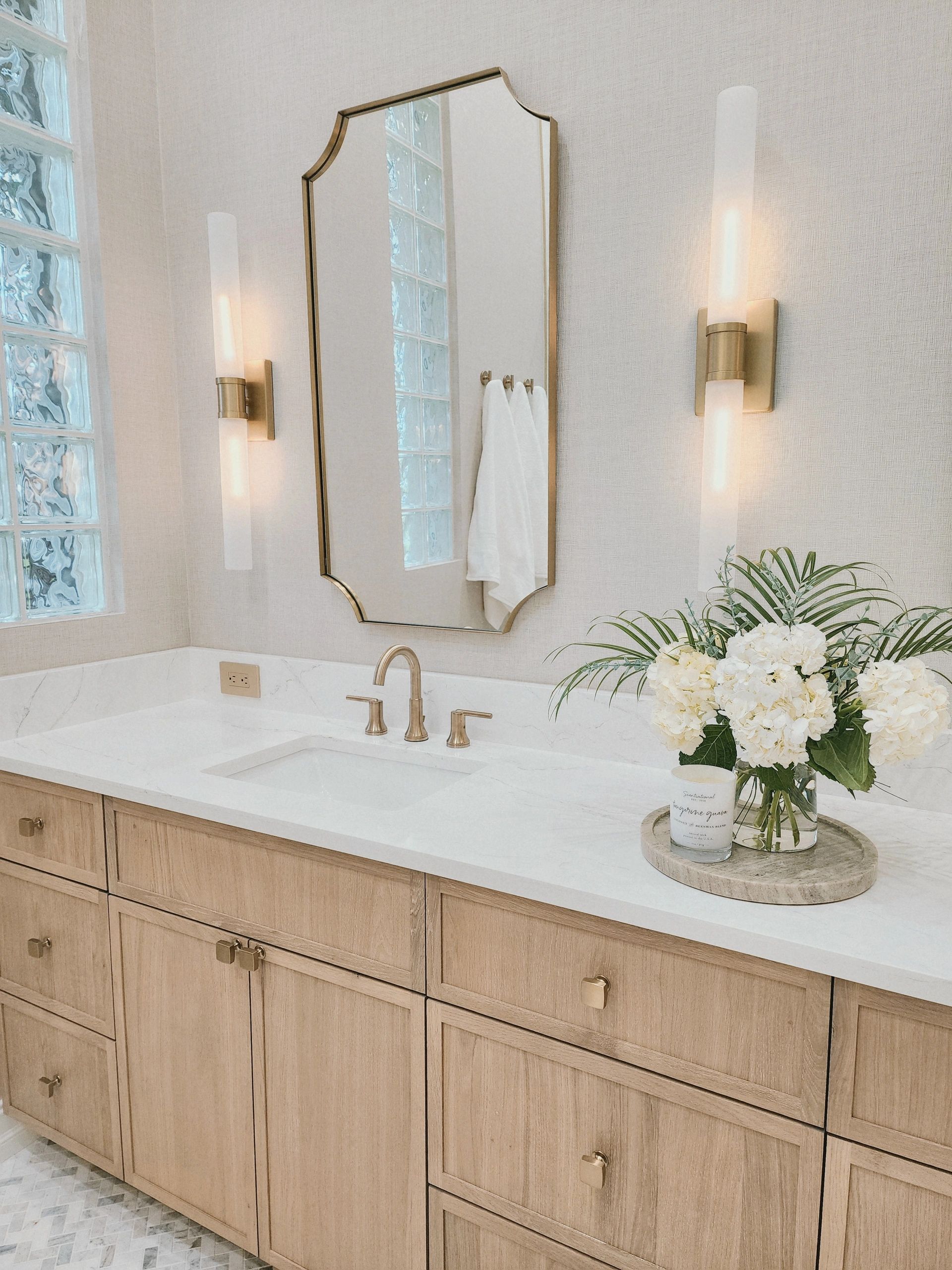 Modern bathroom with wooden cabinets and elegant lighting.