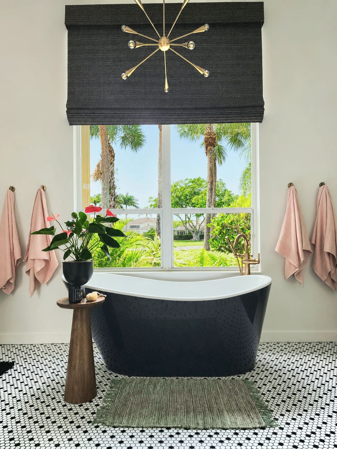 Stylish bathroom with black bathtub and large window overlooking greenery.