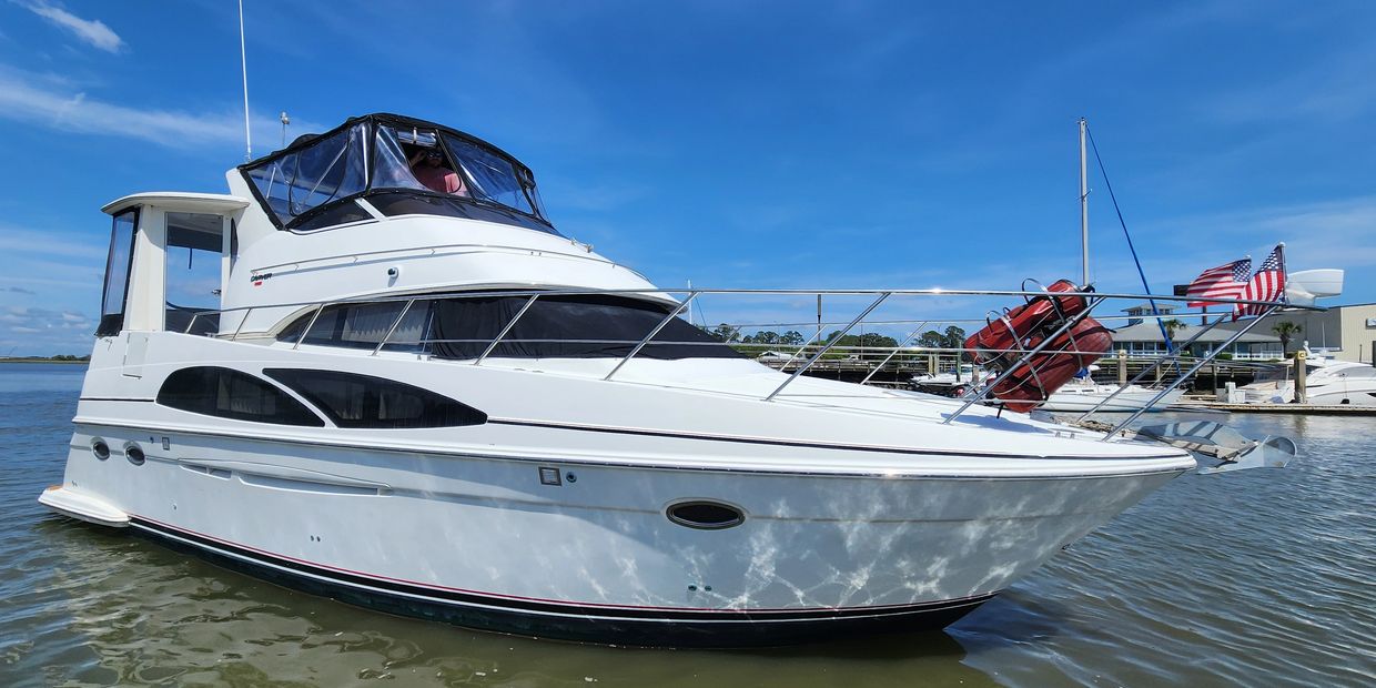 White luxury motor yacht docked by the marina under clear blue sky.