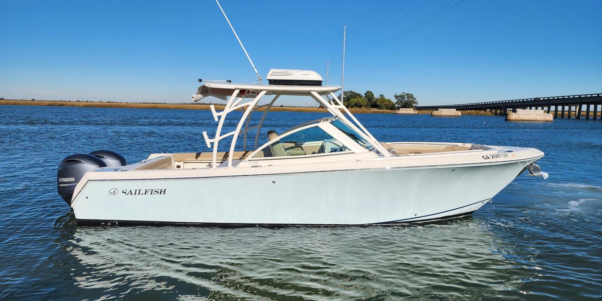 A white Sailfish motorboat floats on calm water under a clear sky.