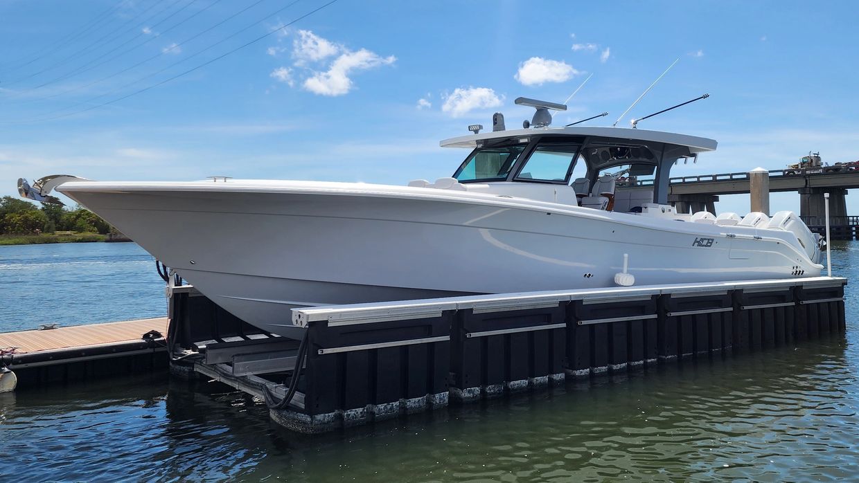 A sleek white motorboat docked on calm water under a clear blue sky.