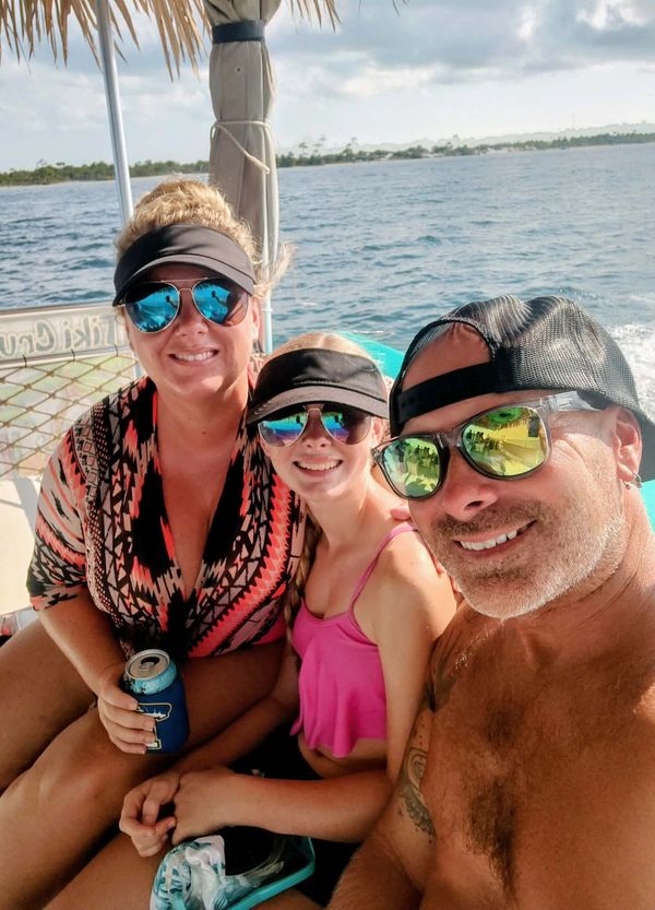 Three people in sunglasses enjoying a boat ride on the ocean.